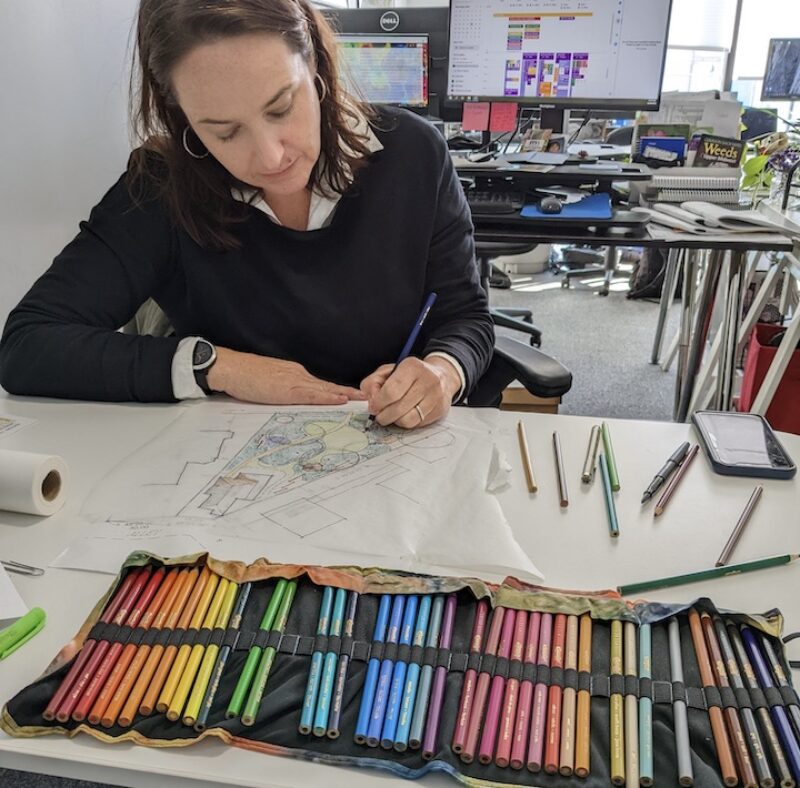 person at table drawing with different colors pencils in ront