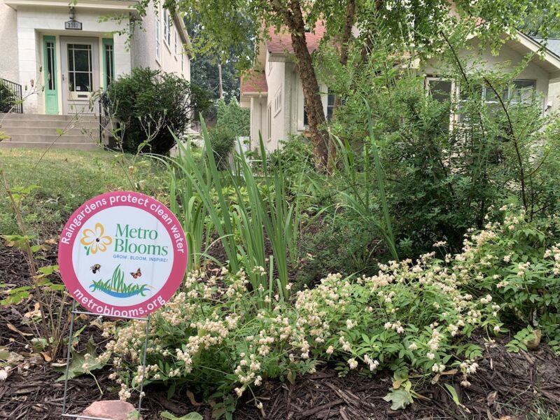 garden in front of house with sign logo for Metro Blooms Design and Build