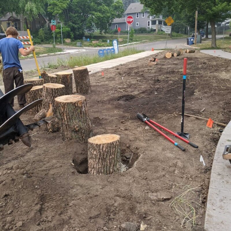 Person installing tree stumps in green space to function as play elemnts